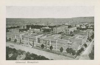 An aerial photograph of a large hospital with a street in front of and to the right, and severa ...