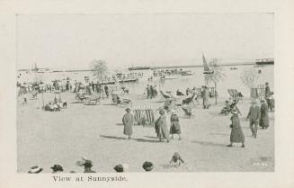 A photograph of a public beach, with a large number of people walking on the beach while wearin ...