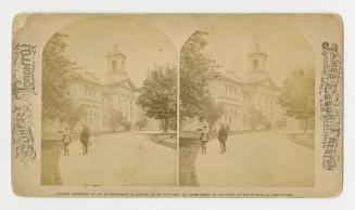 Pictures show two people standing on a path in front of a very large, classical building.