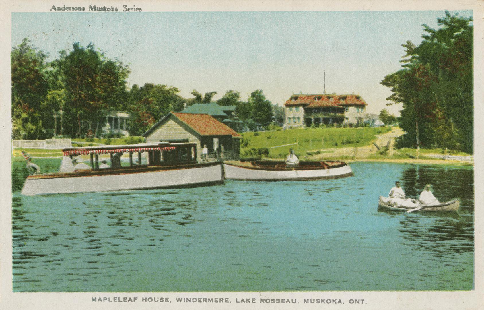 Boats on a lake in front a a boathouse and resort hotel.
