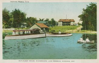 Boats on a lake in front a a boathouse and resort hotel.