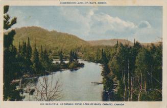 Picture shows a river flowing through hilly wilderness.