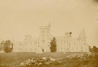 Pictures show a massive collegiate-gothic complex on a hill with trees in front of it.