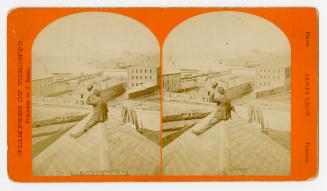 Pictures show a man sitting on top of a roof looking southwest direction over city roof tops.