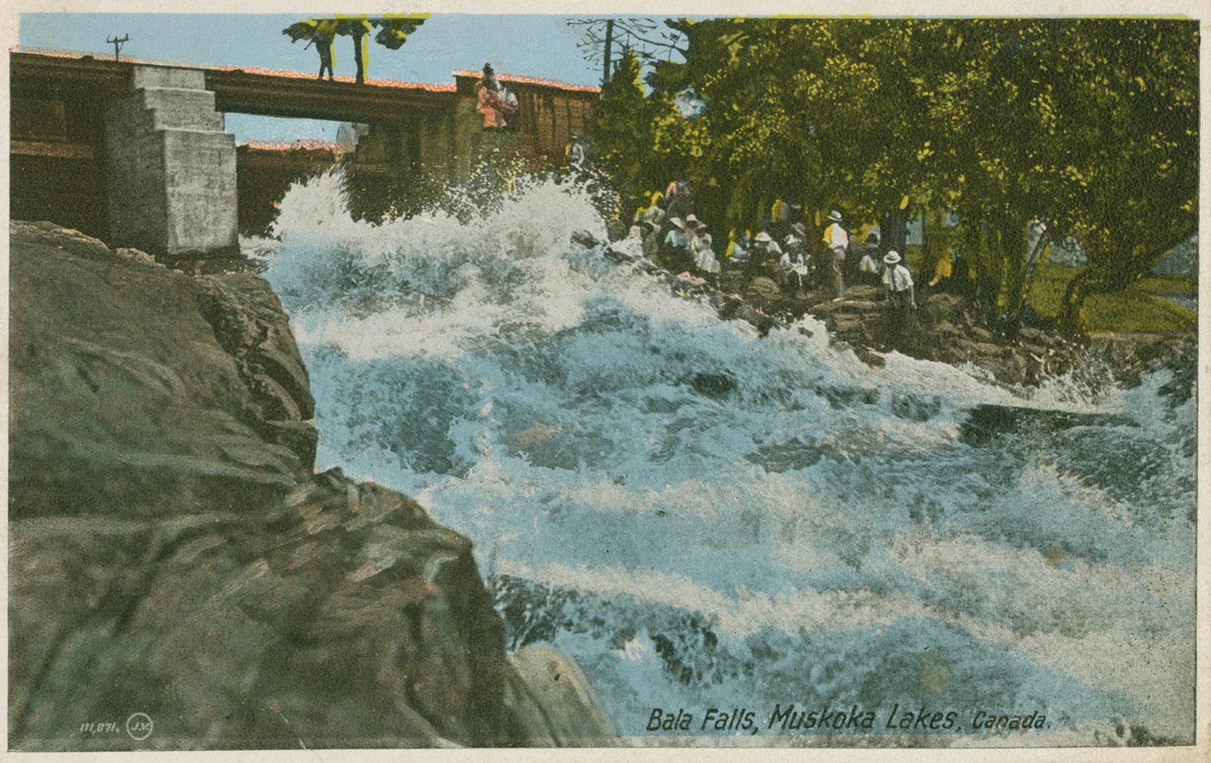 Colorized photograph of a bridge spanning a waterfall. Rocks in the foreground.