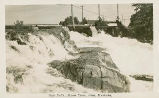 Black and white photograph of a bridge spanning a waterfall.