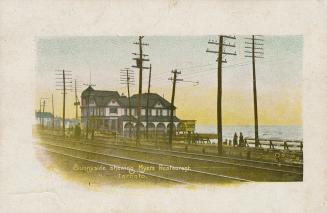 Picture of railway tracks and hydro poles with building on the water. 