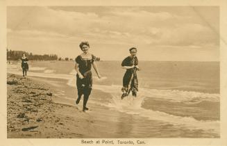 Three women in bathing suits run along a beach at the water's edge. 