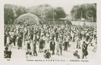 Picture of a large group of couples dancing at an outdoor space. 