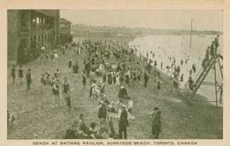 Picture of a wide beach crowded with people and pavilion on the left. 