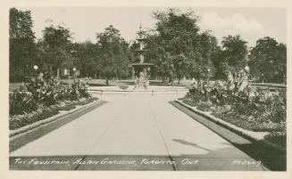 Black and white picture of a large fountain in a city garden.