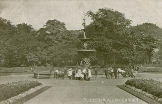 Black and white picture of people in front a large fountain in a city garden.