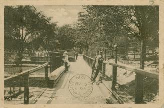 Black and white picture of people leaning over the railings of cages.