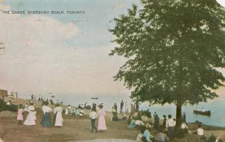 Picture of people standing and sitting on a beach with large tree on right. 