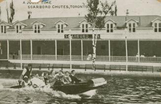 Several people in a boat pass in front of a large inn with a verandah. 