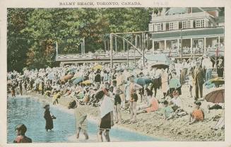 A huge crowd of people on a beach in front of a large structure with a veranda.