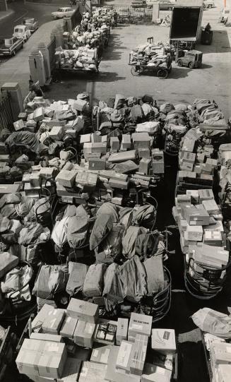 Toronto parcels piling up. Hundreds of bags of mail and parcel post pile up in courtyard of Toronto post office's city delivery building. At top left,(...)