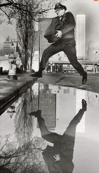 Letter carrier Douglas Strudwick leaps over a puddle on leaving Post Office city delivery building on Lake Shore Blvd, today on the way to his route o(...)