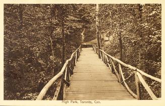 Sepia toned picture of a wooden bridge in a heavily treed area.