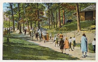A large group of people walking on a pathway through a wooded area. Some are looking at a buffa ...
