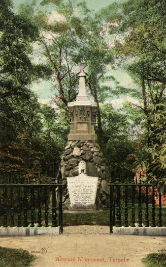 A stone monument in a park behind an iron fence.
