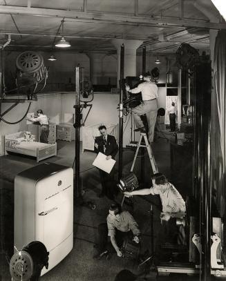 A photograph of a studio area with a high ceiling and lighting rigs illuminating a set with a r ...