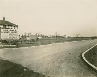 A photograph of a suburban neighbourhood under construction and being promoted on a billboard r ...