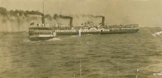 Picture of a large steam boat passing another in the lake. 