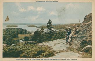 A man and a woman look out from a rocky ledge over a large lake.