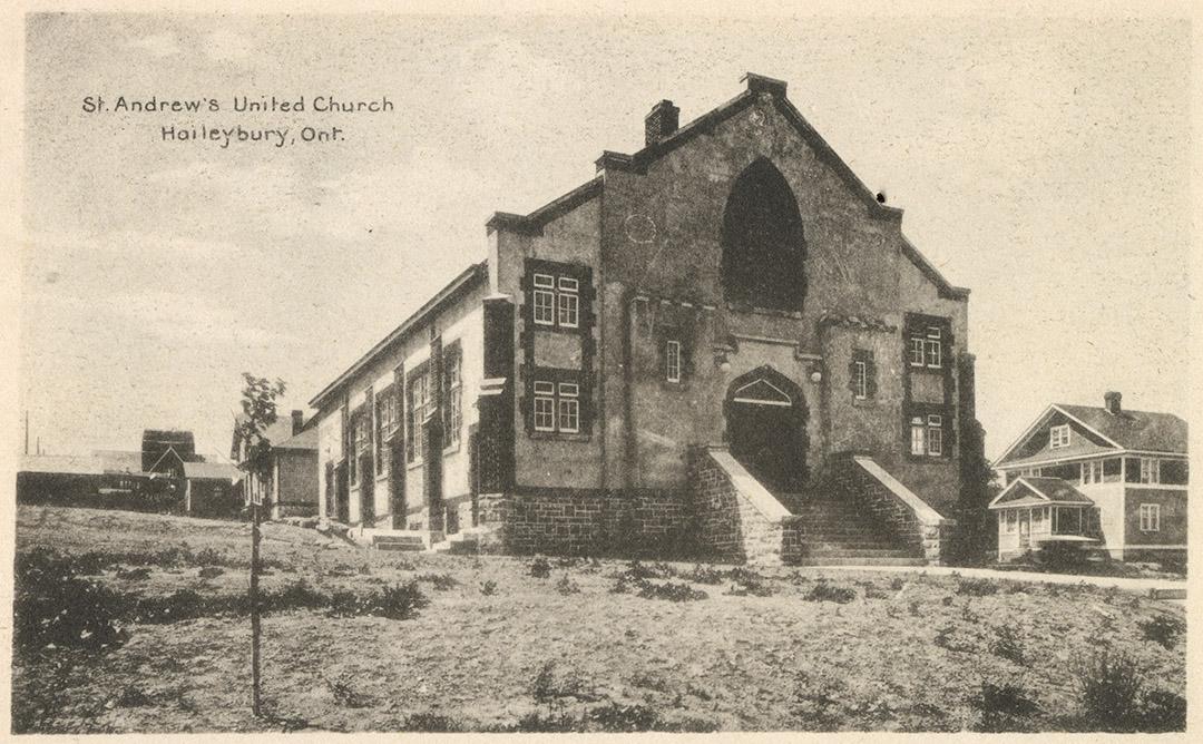 Picture of a newly built stone church with a house across the street from it.