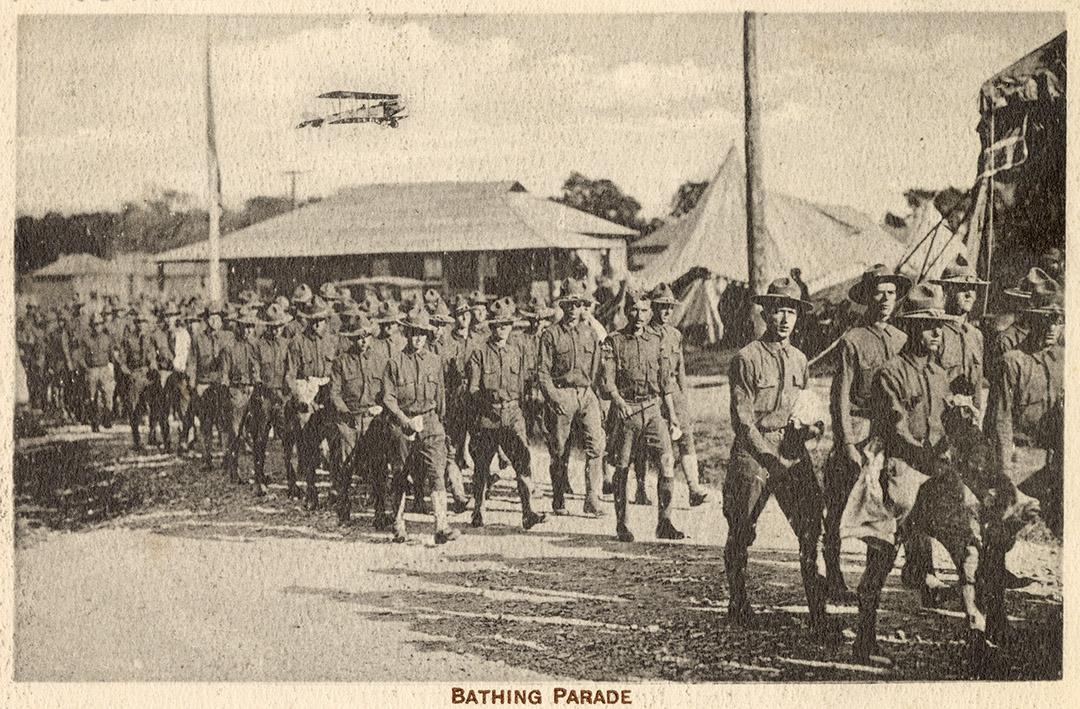 Sepia toned picture of a group of airmen marching through a military camp.