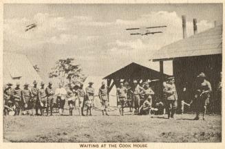 Sepia toned picture of a group of airmen outside buildings in a military camp. Planes are flyin ...