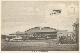 Sepia tone picture of two airplanes on the ground in front of a large, commercial building. Ano ...