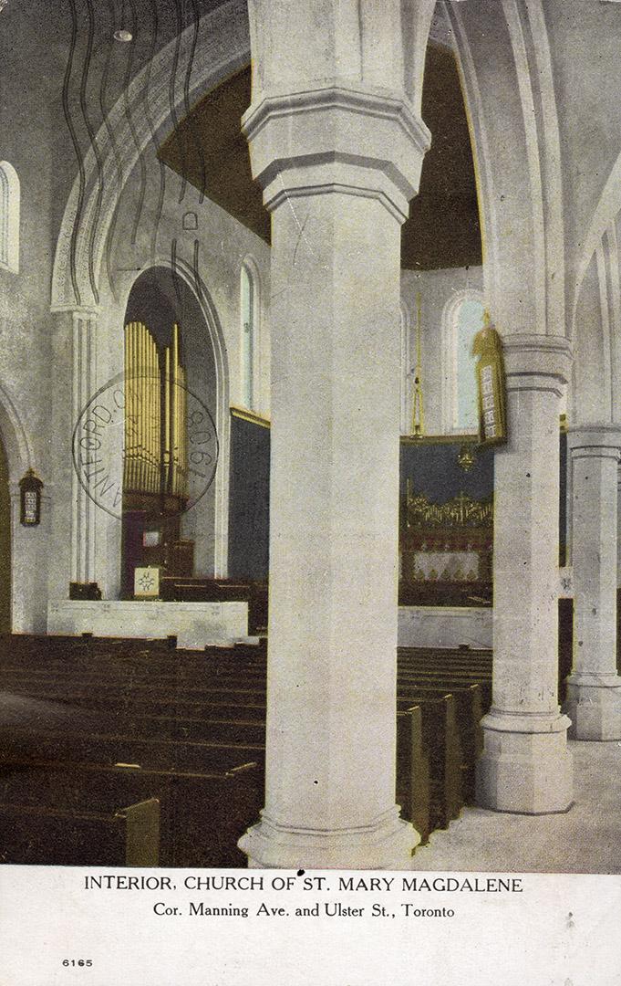 Interior of church with large stone pillars, rows of pews and organ. 
