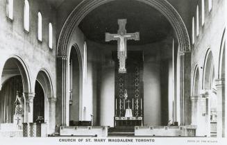 Interior of church with arches and a large cross. 