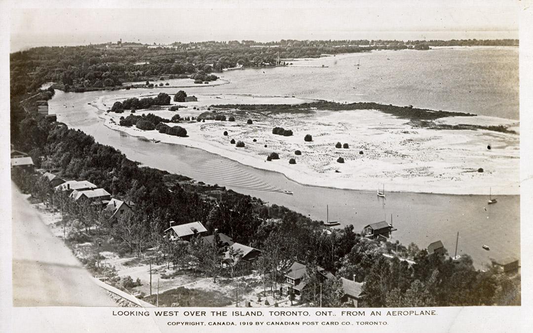 Aerial shot of large of a row of houses on the shoreline of a beach and lake. B & W.