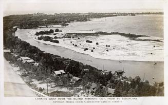 Aerial shot of large of a row of houses on the shoreline of a beach and lake. B & W.