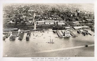Aerial shot of a large city with skyscrapers and a harbor beside a lake. B & W