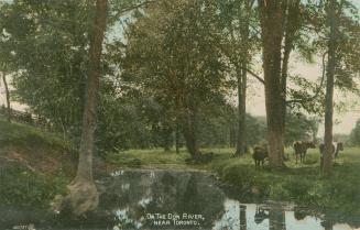 Colorized photograph of a river surrounded by trees with cows grazing beside it.