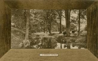 Sepia-toned photograph with a wooden frame of a river surrounded by trees with cows grazing bes ...