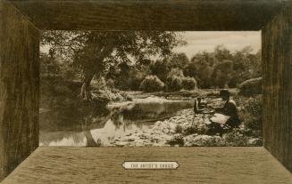 Sepia-toned photograph in a wooden frame of an artist sitting on a stool by a river painting th ...