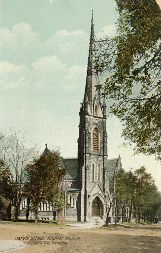 Picture of large stone church on street corner with prominent steeple and trees surrounding it. ...