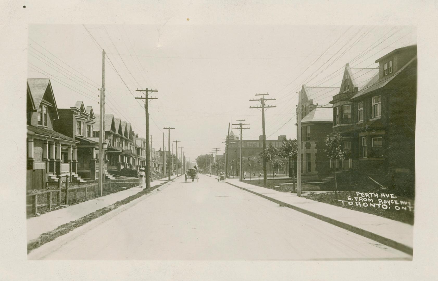 Black and white photograph of a horse and buggy driving down a street with houses on either sid…