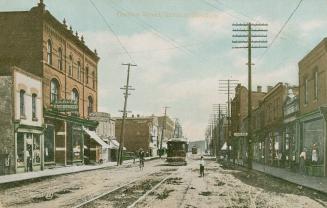Colorized photograph a busy city street with three story buildings on either side.