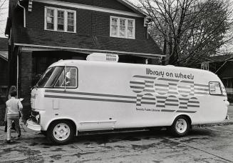 Bookmobile parked in front of a house. 