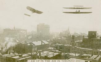 Black and white photograph of two airplanes flying over a large city.