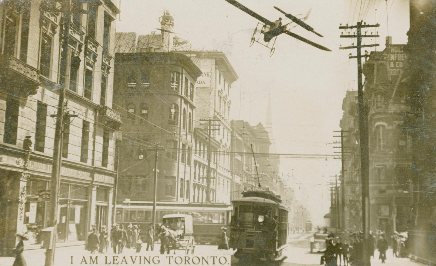 Black and white photograph of an airplane flying over a busy city street.