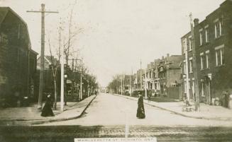 Black and white photograph of a street lined with two story houses.