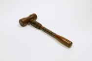 A smooth polished wooden gavel, reinforced by metal bands on the handle.
