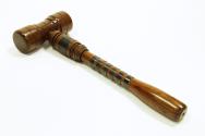 A smooth polished wooden gavel, reinforced by metal bands on the handle.